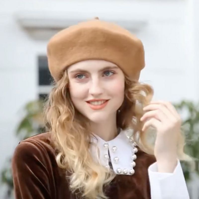 Jeune fille souriante arborant un béret classique Braque de style français en feutre de laine, avec son cabillou traditionnel - coloris marron clair