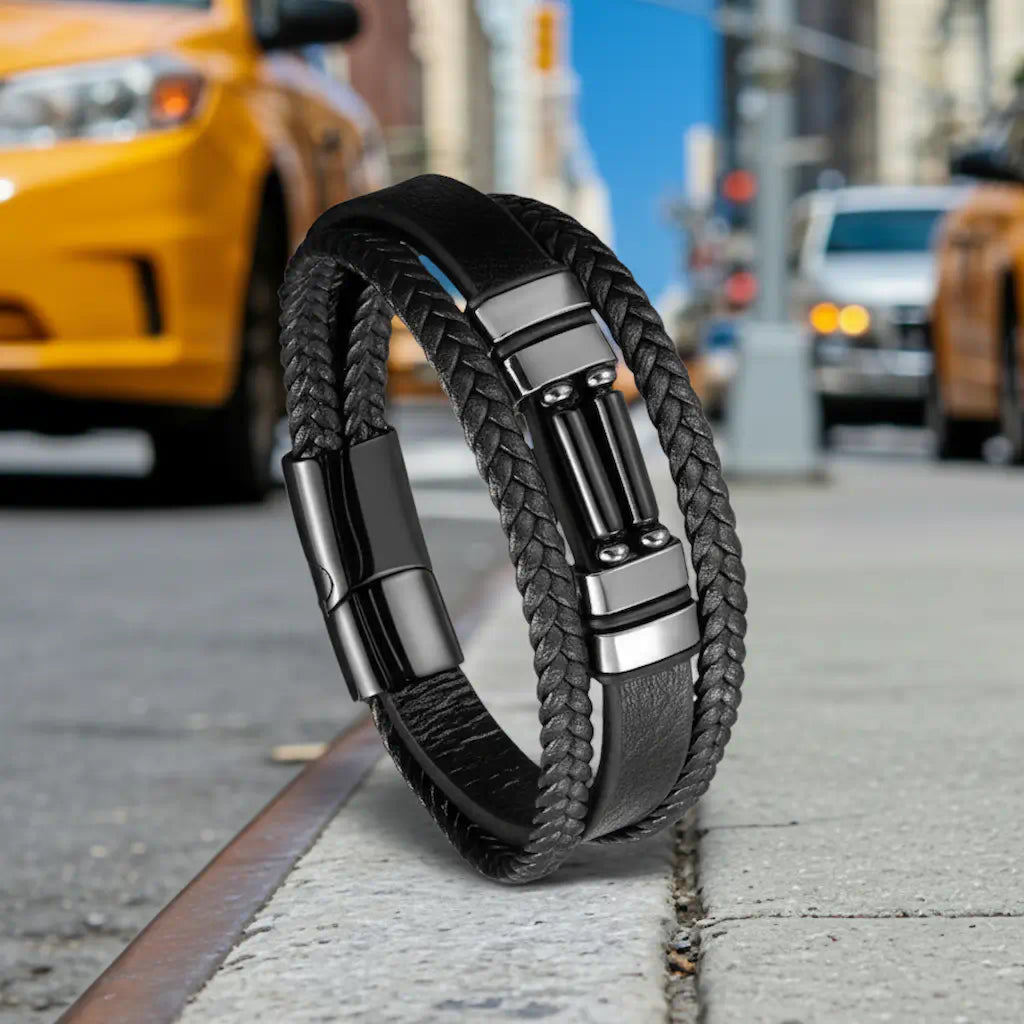 Une mise en scène audacieuse où le bracelet Éclipse en cuir noir défie l'équilibre sur le bitume, mettant en relief l'ergonomie de son fermoir magnétique face au flux dynamique du trafic urbain en arrière-plan.