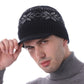 Bonnet sport Fargo à visière en laine grise sur la tête d'un homme tenant de la main droite la visière et vêtu d'un pull gris à col roulé 