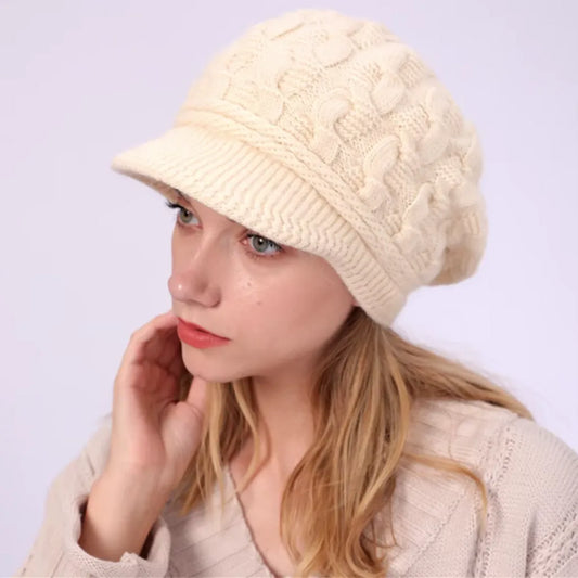 Bonnet pour femme avec visière en laine mélangée, modèle Ashley, porté par un mannequin aux cheveux blonds. Coloris beige avec motif torsadé, pour une touche de féminité et d’originalité.