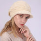 Bonnet pour femme avec visière en laine mélangée, modèle Ashley, porté par un mannequin aux cheveux blonds. Coloris beige Timone avec motif torsadé, offrant un style sobre et raffiné.