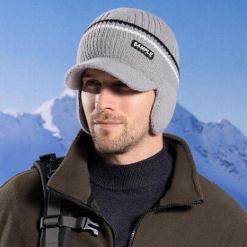 Vue en haute montagne d'un homme portant un bonnet Oslo, visière et cache oreilles en laine acrylique gris clair - chaud et doux
