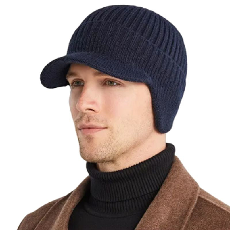 Vue de trois-quart face d'un bonnet à visière Sapporo avec cache-oreilles enfoncé sur la tête d'un homme au col roulé noir - fabriqué en laine acrylique de couleur bleu marine