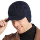 Vue d'un jeune homme souriant arborant un bonnet à visière Sapporo avec cache-oreilles en laine acrylique chaude et douce - coloris bleu marine