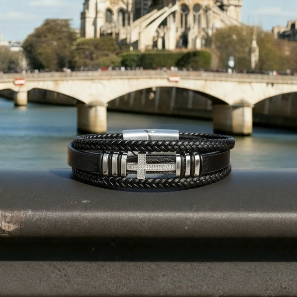 Vue de face. La croix latine en acier brille sur le cuir noir multi-rangs, soulignant le pouvoir du symbole sur le quai de la Seine.