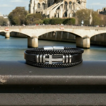Vue de face. La croix latine en acier brille sur le cuir noir multi-rangs, soulignant le pouvoir du symbole sur le quai de la Seine.