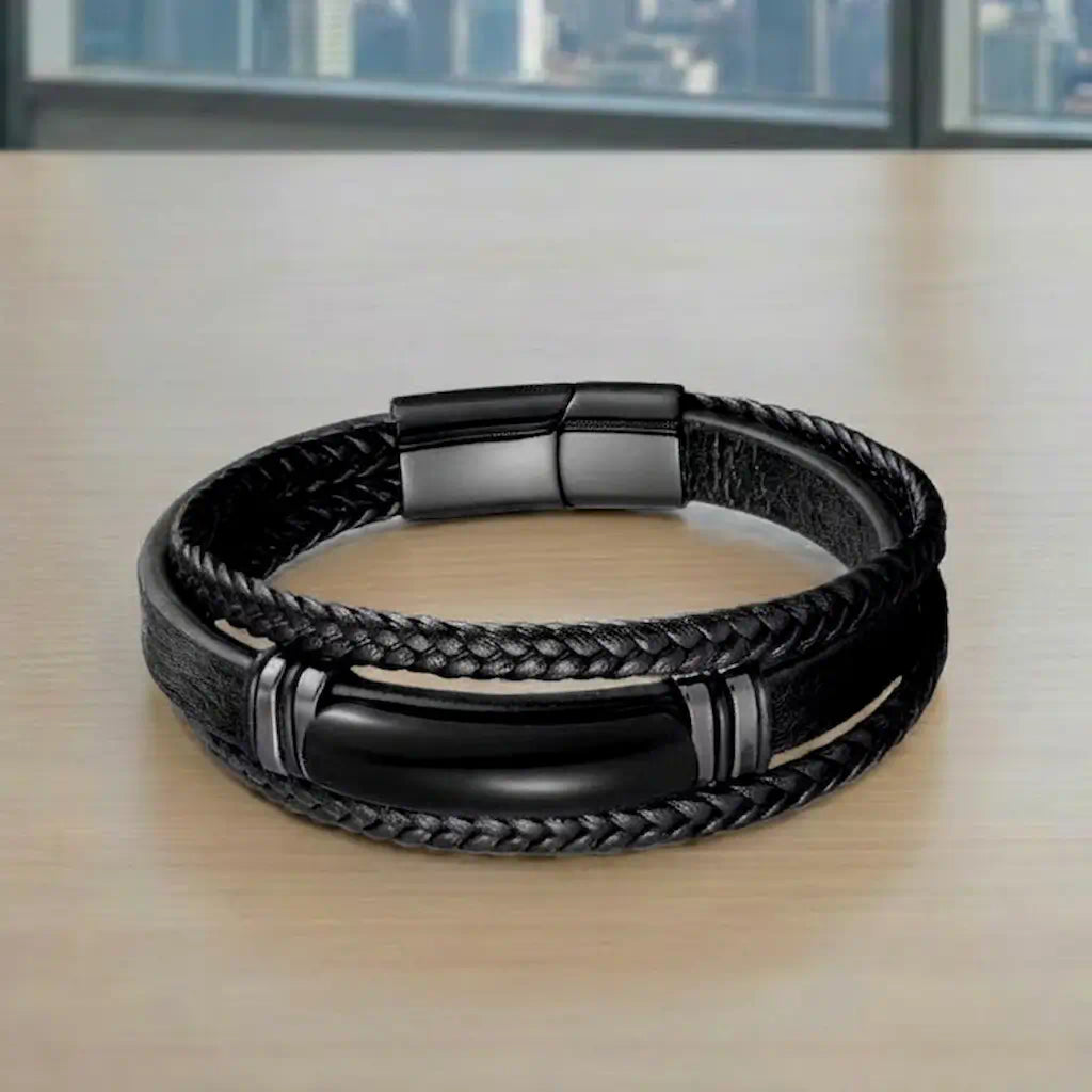 Vue de face du Bracelet Obsidian posé à plat, exposant son motif central en agate noire et son cuir noir souple sur une surface de travail urbaine.