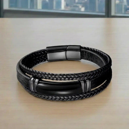 Vue de face du Bracelet Obsidian posé à plat, exposant son motif central en agate noire et son cuir noir souple sur une surface de travail urbaine.