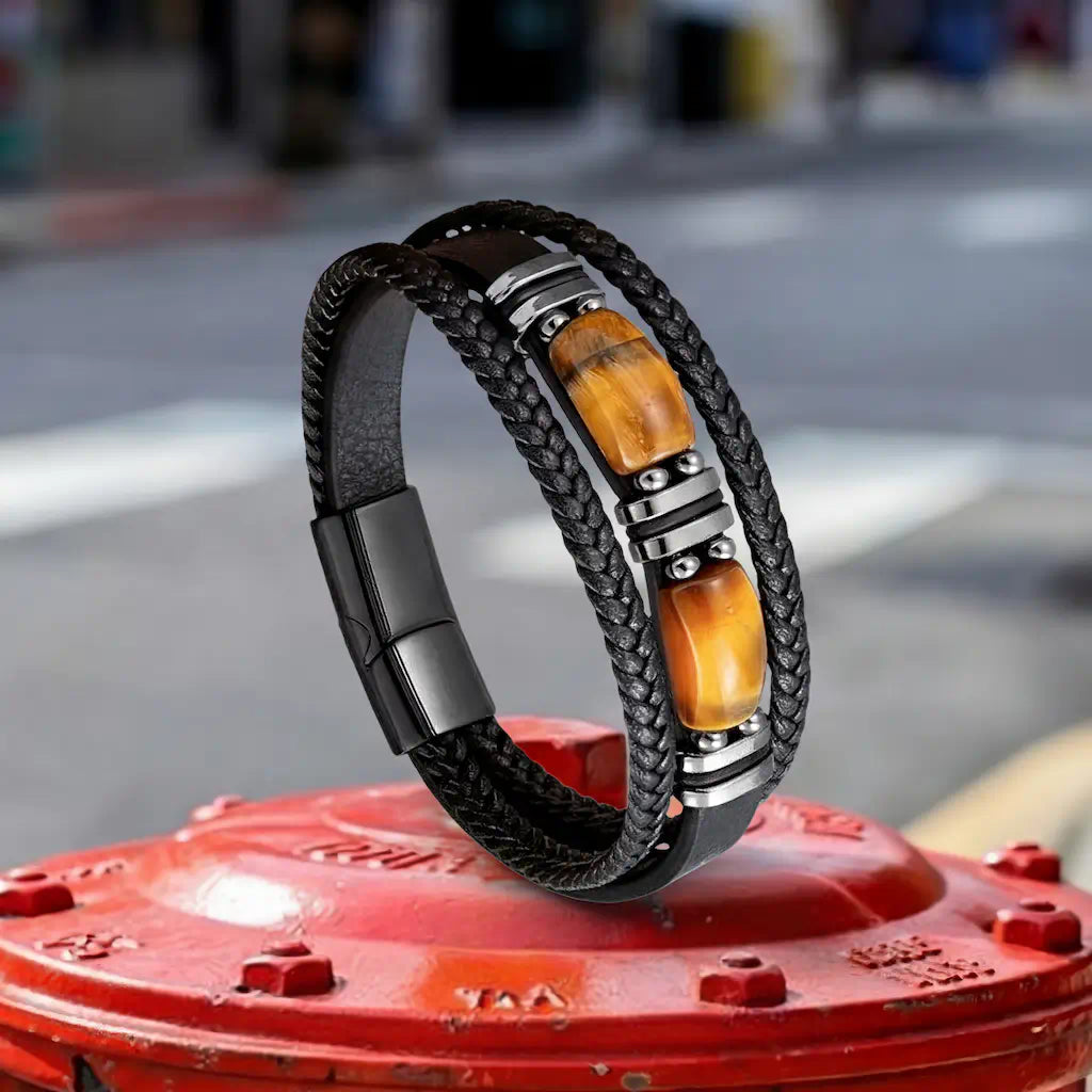 Perspective de profil du bracelet Apex en équilibre, soulignant la souplesse de son cuir noir et l'alignement parfait de ses six bagues en acier noirci sur un fond industriel coloré et dynamique.