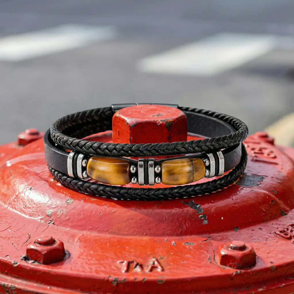 Détail artistique du bracelet Apex enroulé autour d'un écrou de fonte rouge, illustrant la fusion entre l'élégance des pierres œil de tigre et la robustesse des accessoires de mode masculine d'inspiration métropolitaine.