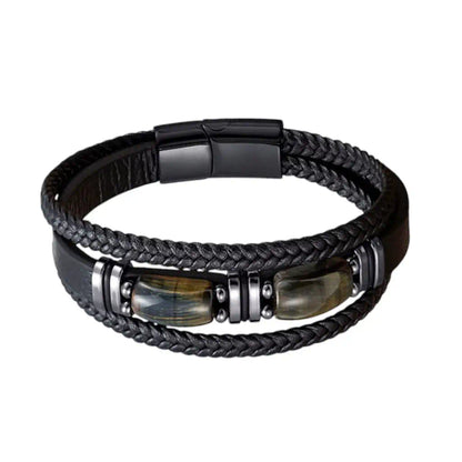 Vue frontale du bracelet Apex révélant sa structure multi-rangs en cuir noir aux textures contrastées, où deux gemmes d’œil de tigre aux reflets bleus scandinave sont encadrées par des bagues en acier sur un fond épuré.