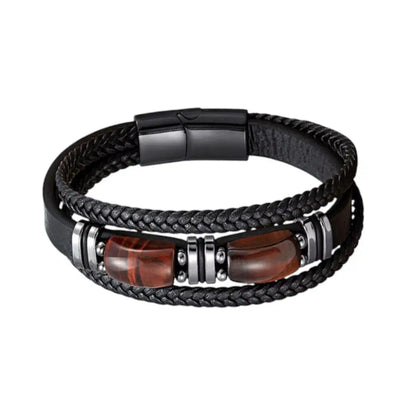 Vue frontale du bracelet Apex révélant sa structure multi-rangs en cuir noir aux textures contrastées, où deux gemmes d’œil de tigre aux reflets braises rouges cognac sont encadrées par des bagues en acier sur un fond épuré.