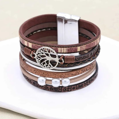 Bracelet arbre de vie multi-rangs en cuir microfibre marron avec perles couleur nacre, fermoir magnétique, posé sur assiette.