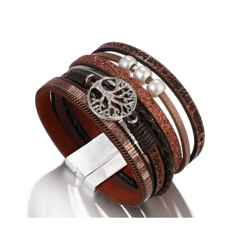 Vue de haut d'un bracelet avec une breloque représentant un arbre de vie, wrap bohème perlé pour femme posée sur son fermoir magnétique en alliage, son cuir PU doux est de couleur marron.