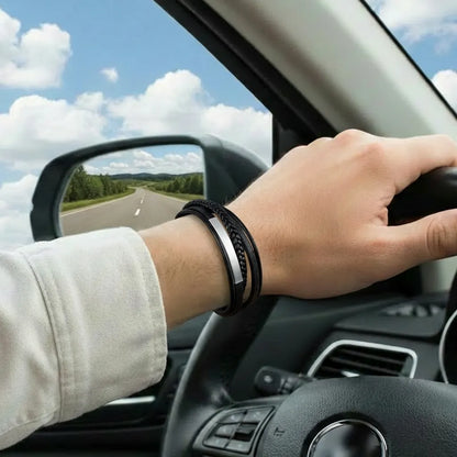 Très gros plan. Le bracelet Axis cuir souple noir porté, main sur le volant. Le tube rectangulaire et le design multi-rangs se fondent dans l'esthétique du conducteur moderne.