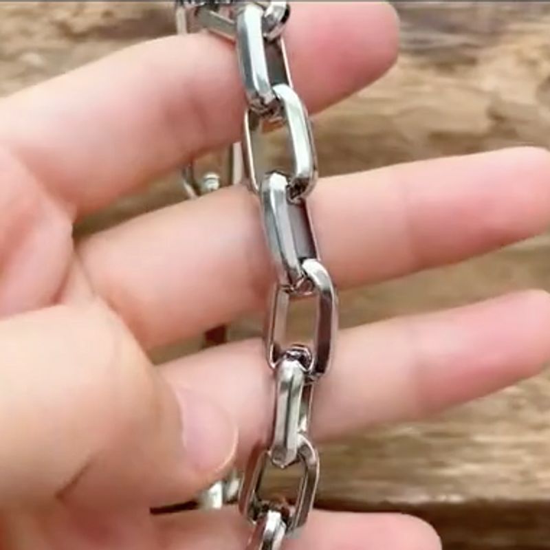 Bracelet chaîne d'ancre à maillons rectangulaires entre les doigts d'une main d'homme - acier inoxydable de coloris argent