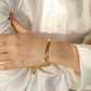 Bracelet chaîne à maillions plats cubains en acier inoxydable présenté sur un poignet de femme aux bras croisés vêtu d'une chemise blanche aux manches longues - zircone cubique -bijou femme - coloris plaqué or 18 K