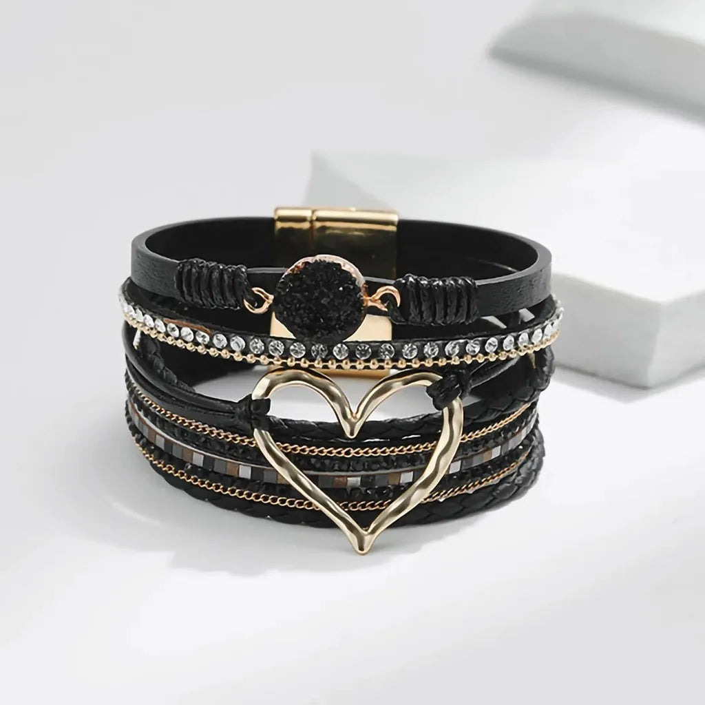 Vue frontale du bracelet Cœur de Lune Vagabonde noir. Le cœur ajouré doré et la pierre résine à l'effet druse sont au centre de l'attention, sur un fond épuré.