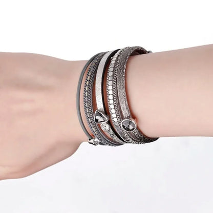 Bracelet Cristal de lumière gris porté sur un poignet nu. Le design multi-rangs en cuir microfibre est mis en valeur.