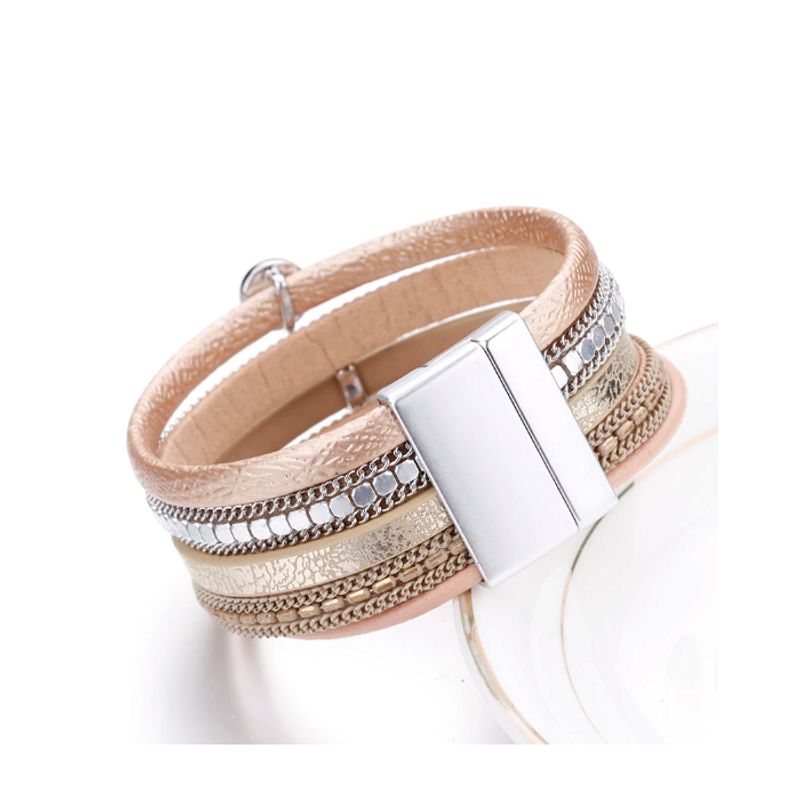 Bracelet bohème cristal strass, wrap en cuir pour femme avec fermoir magnétique en alliage métallique inoxydable posé et incliné sur le bord d'une assiette en porcelaine - couleur champagne