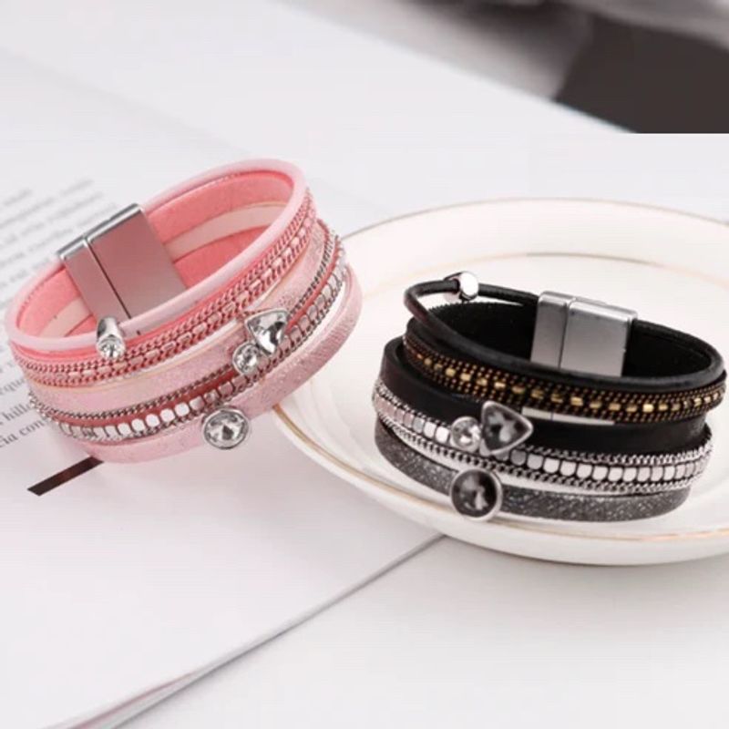 Deux bracelets , même modèle bohème cristal strass, wrap en cuir pour femme avec fermoir magnétique présenté incliné et posé sur une assiette creuse - deux coloris, un rose et l'autre noir