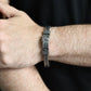 Bracelet avec croix égyptienne Ankh en acier inoxydable vue de face sur un poignet d'homme vêtu de noir - coloris argent