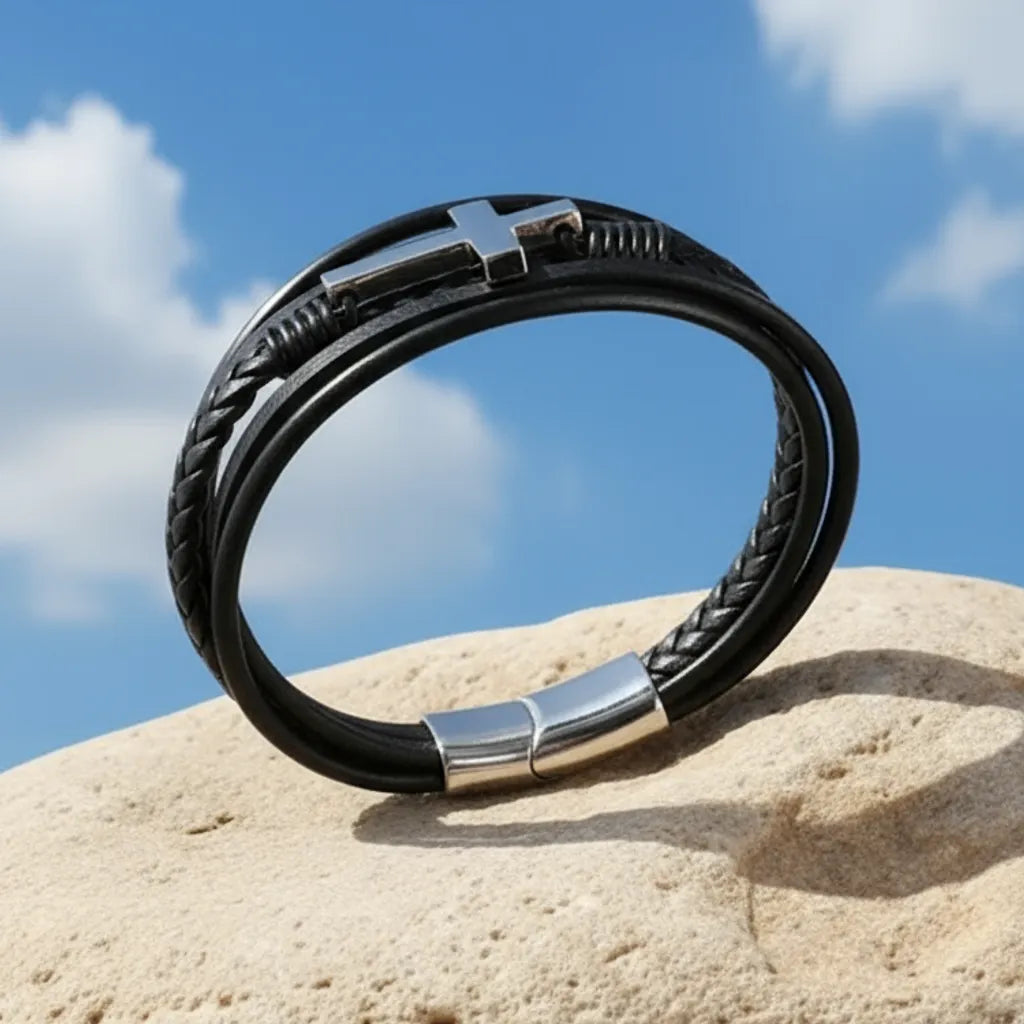 Bracelet en équilibre sur son fermoir sur un rocher. La croix latine est visible sur fond du ciel bleu et nuageux.