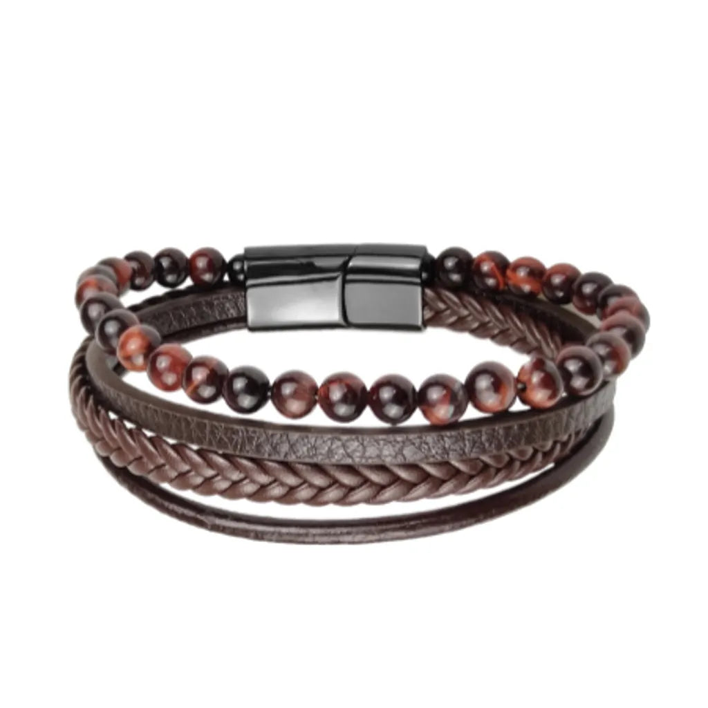 Bracelet en cuir marron authentique avec un fermoir magnétique noir, décoré d'une rangée de perles naturelles : œil de tigre rouge intense. Présenté sur un fond blanc qui fait ressortir la richesse des couleurs et la qualité du cuir.