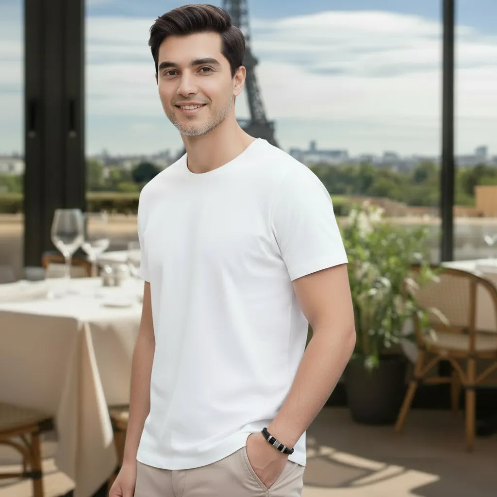 Vue 3/4. Le bracelet Cylindre Pointillé en cuir noir est visible au poignet. La pose (main dans la poche) et le décor du restaurant et de la tour Eiffel ancrent le bijou dans l'esthétique urbaine.