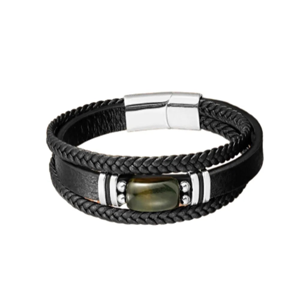 Bracelet pour homme en cuir noir avec double tresse et lanière lisse, orné d'une pierre œil de tigre bleu au centre. Fermoir magnétique argenté solide, offrant une allure élégante et moderne. Accessoire parfait pour rehausser un look masculin avec une touche de sophistication unique.