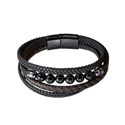 Gros plan du bracelet Oris mêlant cuir tressé bicolore et perles agate noire polie. L'architecture multi-rangs s'achève sur un fermoir magnétique en acier noir, posé sur fond blanc épuré.