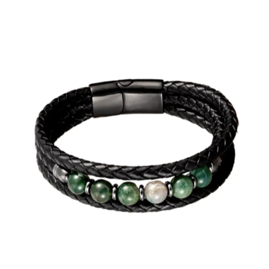 Bracelet en cuir noir tressé avec des perles vertes en aventurine, posé délicatement sur un fond blanc minimaliste, mettant en valeur la texture du cuir et l'élégance naturelle des perles.