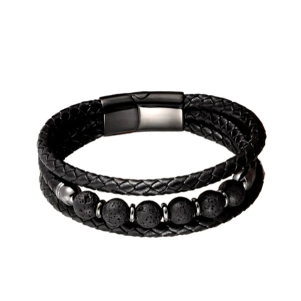 Bracelet en cuir tressé noir avec des perles texturées en pierre de lave noire, posé à plat sur un fond blanc neutre, mettant en avant son design brut et naturel.