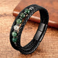 Bracelet en cuir noir tressé avec des perles vertes en aventurine, élégamment posé sur une surface texturée en bois naturel, mettant en valeur son style sophistiqué et son fermoir magnétique noir.