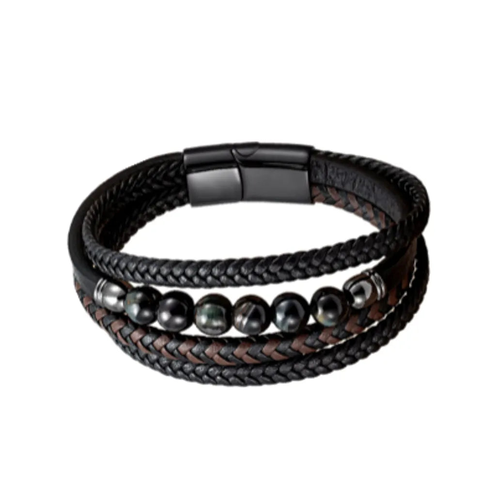 Bracelet en cuir tressé noir et marron, rehaussé de perles en œil de tigre bleu intense, avec un fermoir noir épuré. Le contraste des couleurs crée une esthétique moderne et élégante pour les amateurs de bijoux distinctifs.