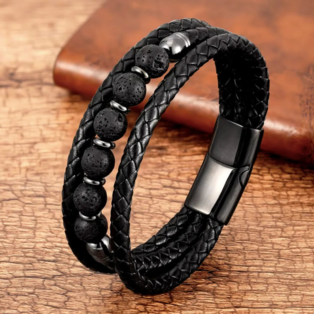 Bracelet en cuir noir tressé avec des perles texturées en pierre de lave noire, magnifiquement posé sur un fond naturel en bois, capturant une esthétique brute et organique.