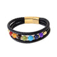 Bracelet en cuir tressé noir, orné de sept pierres colorées représentant les chakras, soigneusement disposées au centre avec des anneaux de couleur or. Le fermoir magnétique doré ajoute une touche luxueuse à ce bijou harmonieux et symbolique.