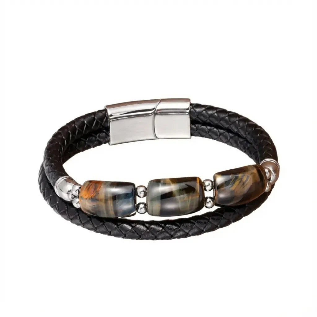 Bracelet tressé en cuir noir avec trois pierres œil de tigre bleu, finement encadrées par des éléments en acier poli. Un accessoire chic et audacieux qui illumine discrètement chaque tenue.
