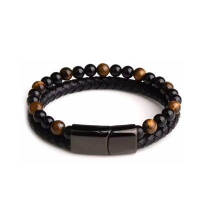 Bracelet double rang en cuir tressé noir, décoré de perles d’œil de tigre jaune doré et d’onyx noire. Le design met en avant un fermoir magnétique noir brillant, ajoutant une touche moderne et élégante. Le bracelet est présenté à plat sur un fond blanc minimaliste, mettant en valeur ses détails raffinés et son style intemporel.