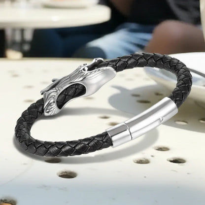 Gros plan du bracelet. Le cuir tressé noir et le fermoir magnétique sont vus de face. On distingue l'arrière lisse du dragon.