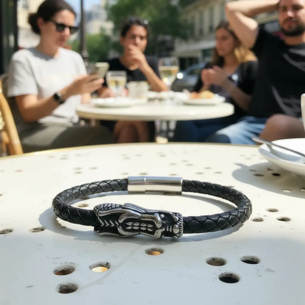 Bracelet Dragon Ouroboros en cuir noir tressé, posé a plat sur un guéridon. Vue de haut de face du dragon en acier inoxydable.