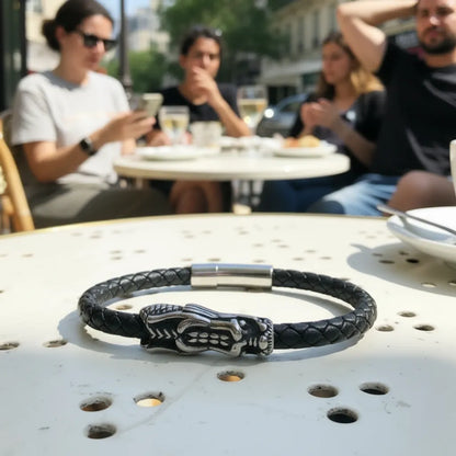 Bracelet Dragon Ouroboros en cuir noir tressé, posé a plat sur un guéridon. Vue de haut de face du dragon en acier inoxydable.