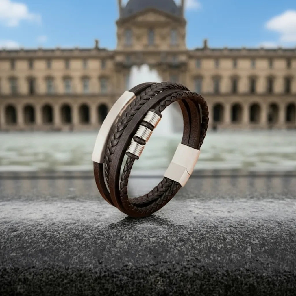 Architecture urbaine. Le bracelet Equinox cuir noir multi-rangs en équilibre sur la margelle de la fontaine, face à la pyramide du Louvre.