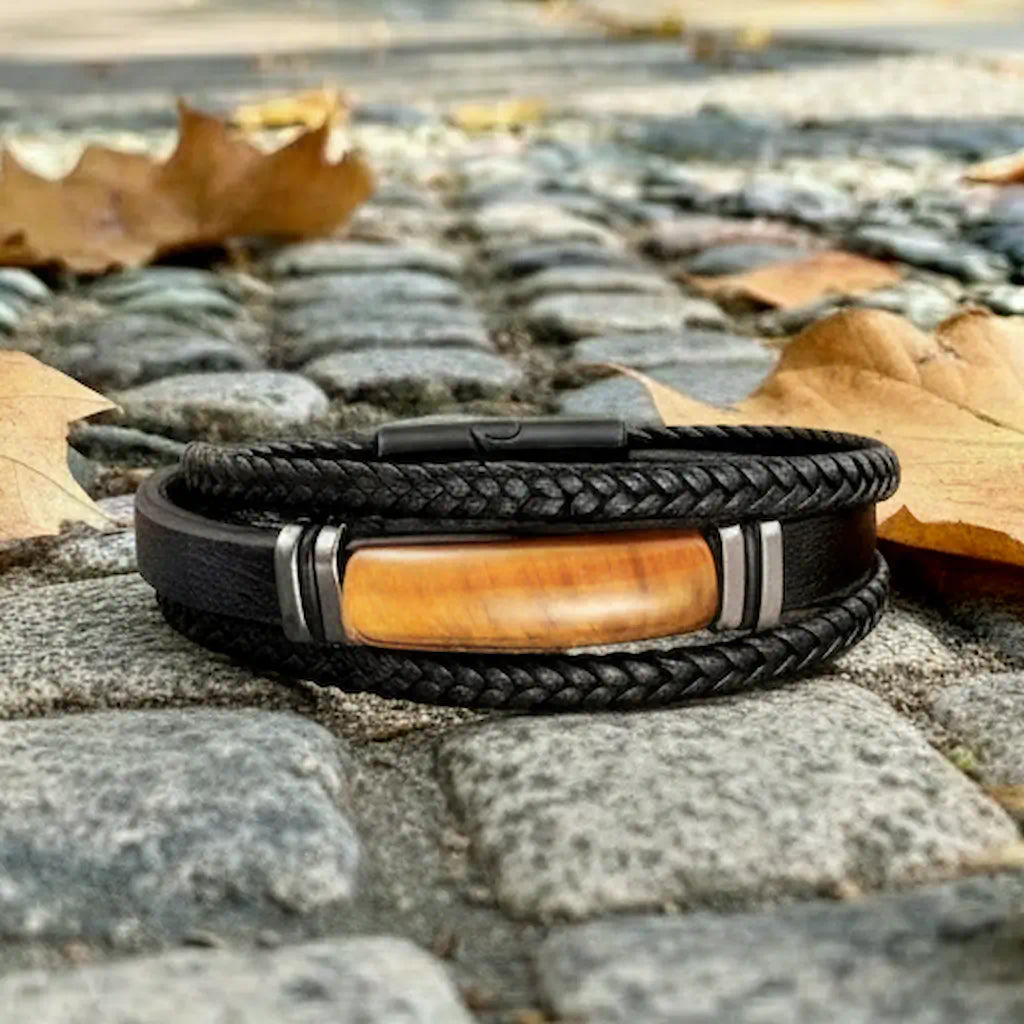 Composition épurée du bracelet Fauve posé à plat parmi des feuilles de platane, où les nuances jaune et brunes de l'œil de tigre répondent aux teintes naturelles du décor urbain.