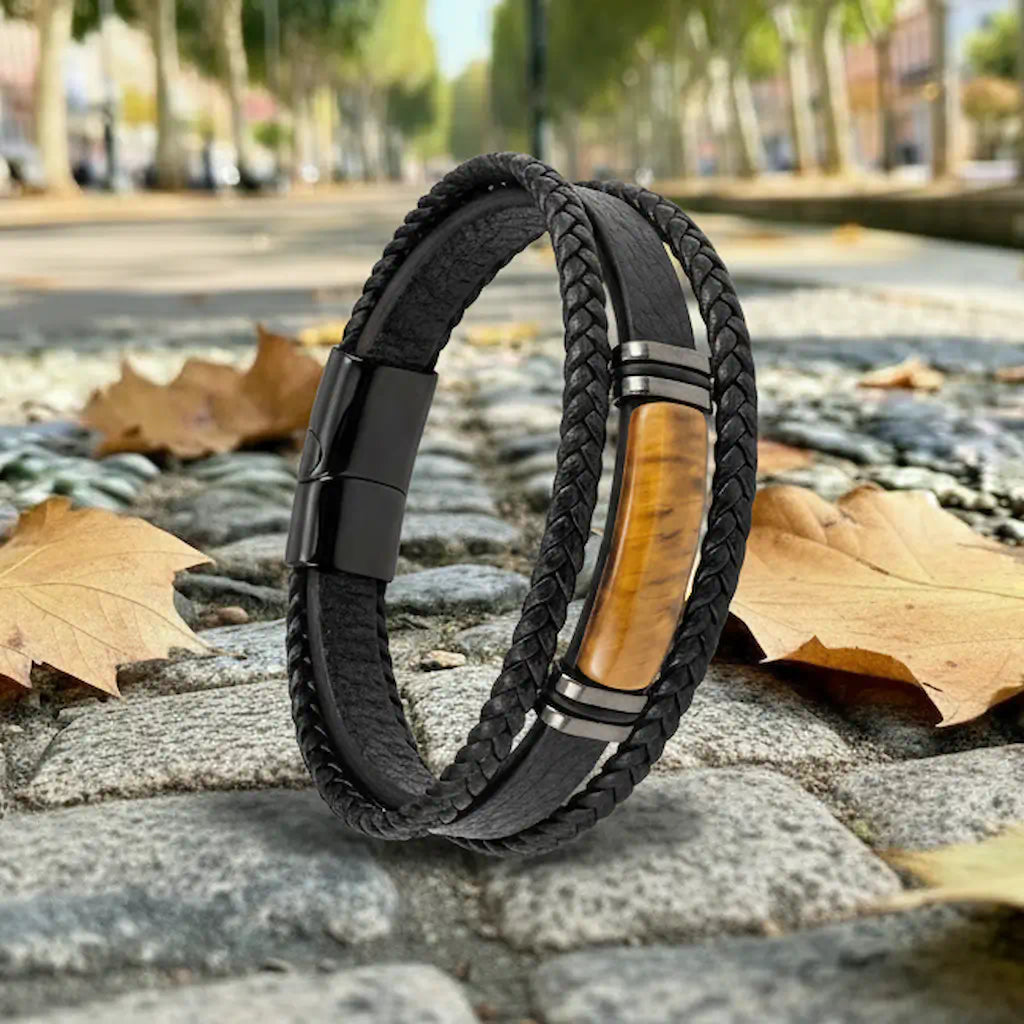 Silhouette inclinée du bracelet Fauve en équilibre sur des pavés anciens, mettant en relief l'architecture tri-rangs et la finition mate du fermoir magnétique noirci.