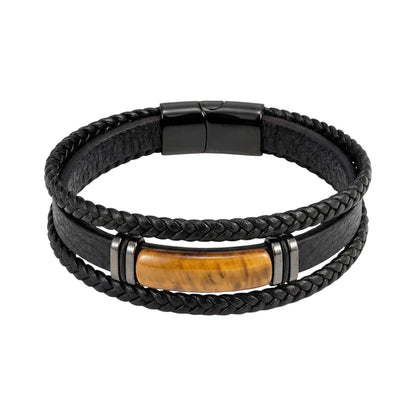 Gros plan du Bracelet Fauve où l'œil de tigre oblong s'enchâsse entre cuir tressé et bagues d'acier. Une symétrie parfaite soulignée par un fermoir magnétique noir sur fond immaculé.