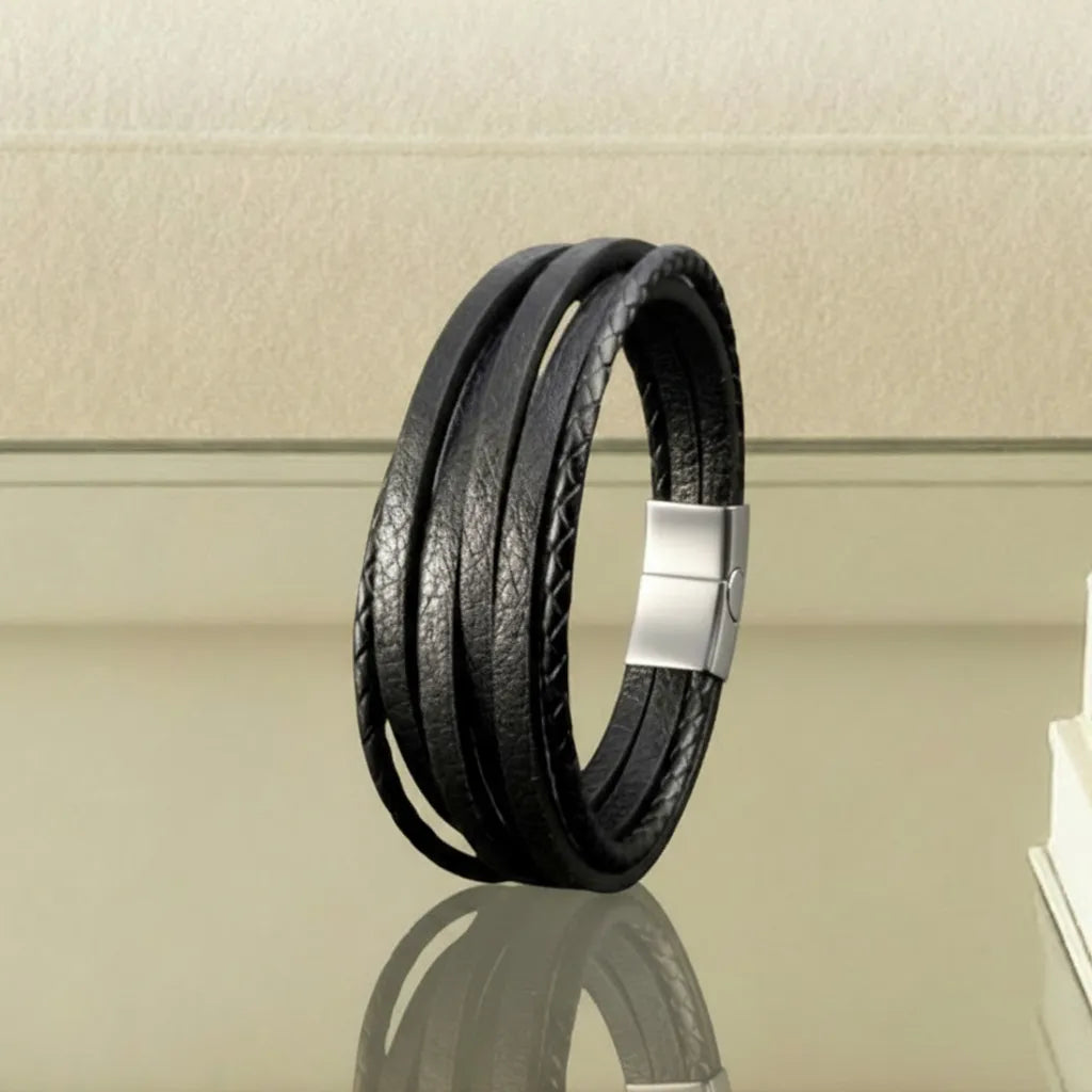 Composition design. Le bracelet Fusion en équilibre sur la table en verre. La construction multi-rangs de cuir souple noir crée un fort effet de volume dans un décor contemporain.