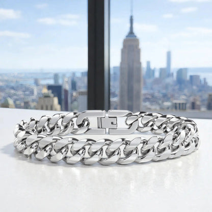 Bracelet gourmette acier argenté posé devant un panorama urbain de gratte-ciels