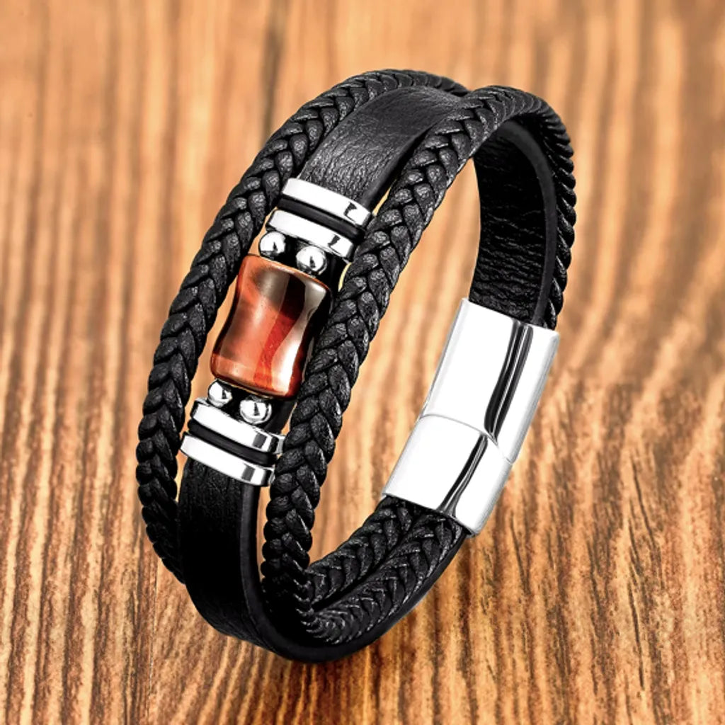 Bracelet pour homme en cuir noir avec une pierre centrale rouge œil de tigre et fermoir magnétique en acier inoxydable argenté. Un accessoire élégant parfait pour un style unique.