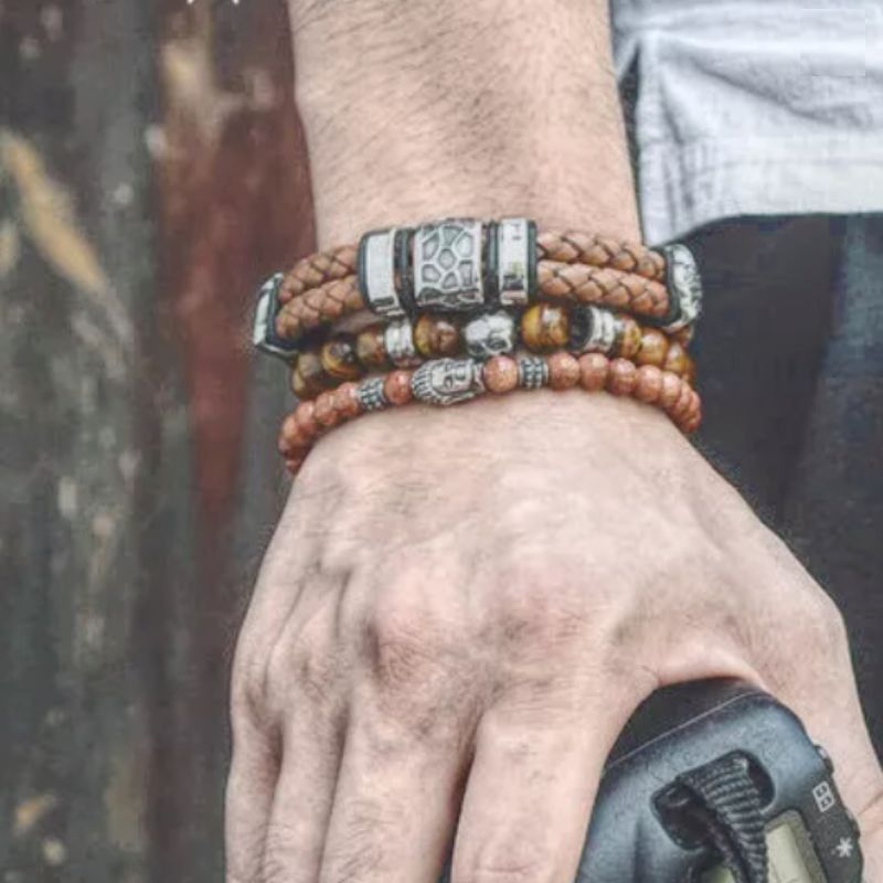 Bracelet en cuir double lanières tressées avec charms terre aride et fermoir magnétique inoxydable porté autour d'un poignet d'homme.